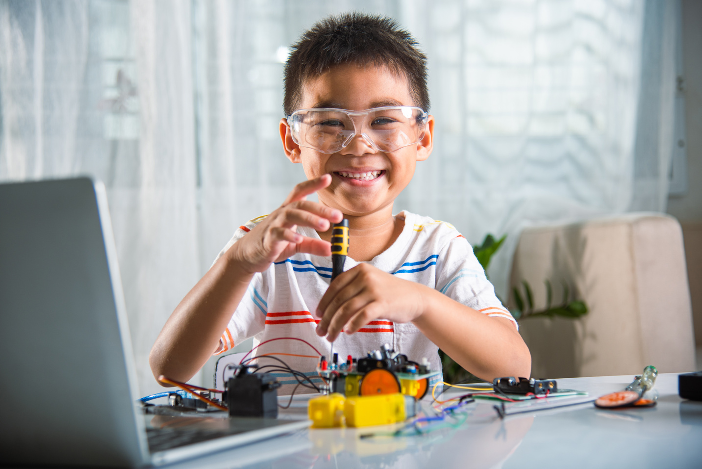 Asian kid boy assembling the Arduino robot car homework project